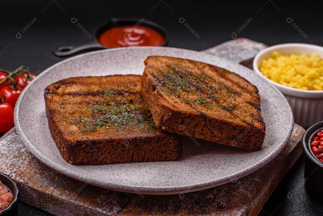 Deliciosos croutons crocantes ou bruschetta de pão integral com molho de alho e ervas sobre um fundo escuro de concreto
