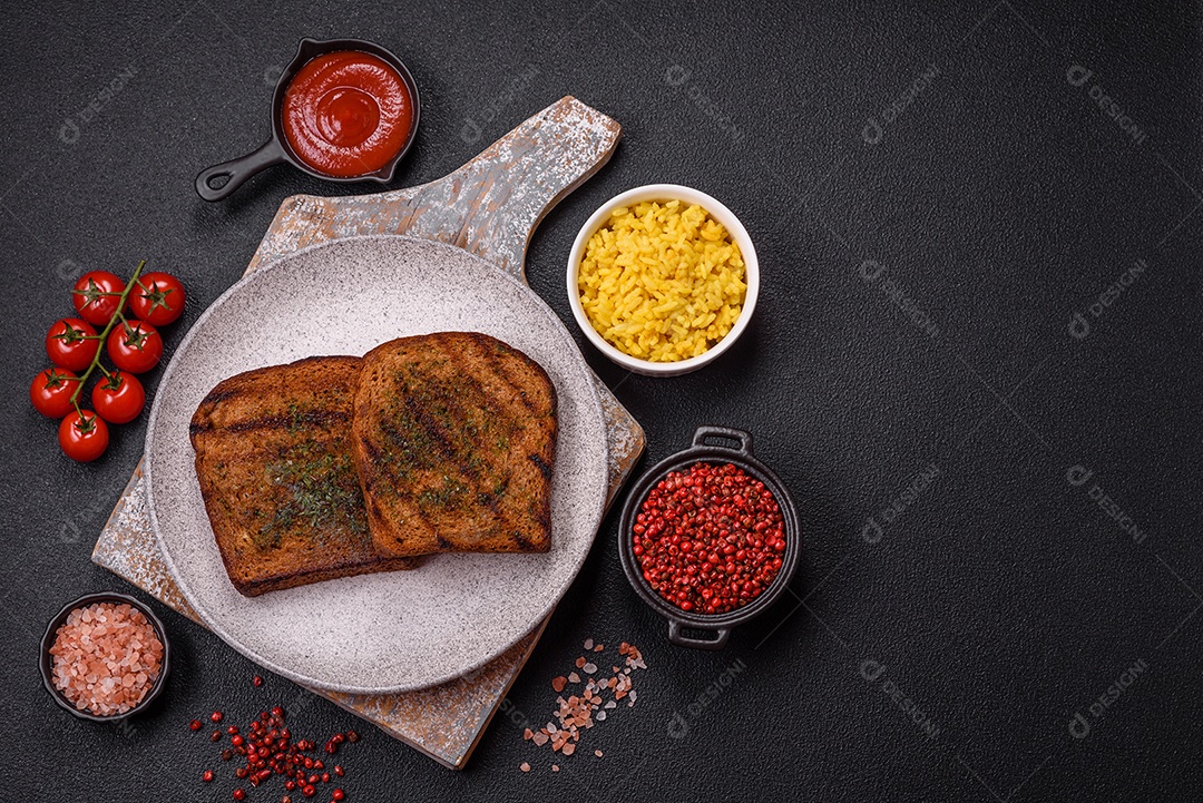 Deliciosos croutons crocantes ou bruschetta de pão integral com molho de alho e ervas sobre um fundo escuro de concreto