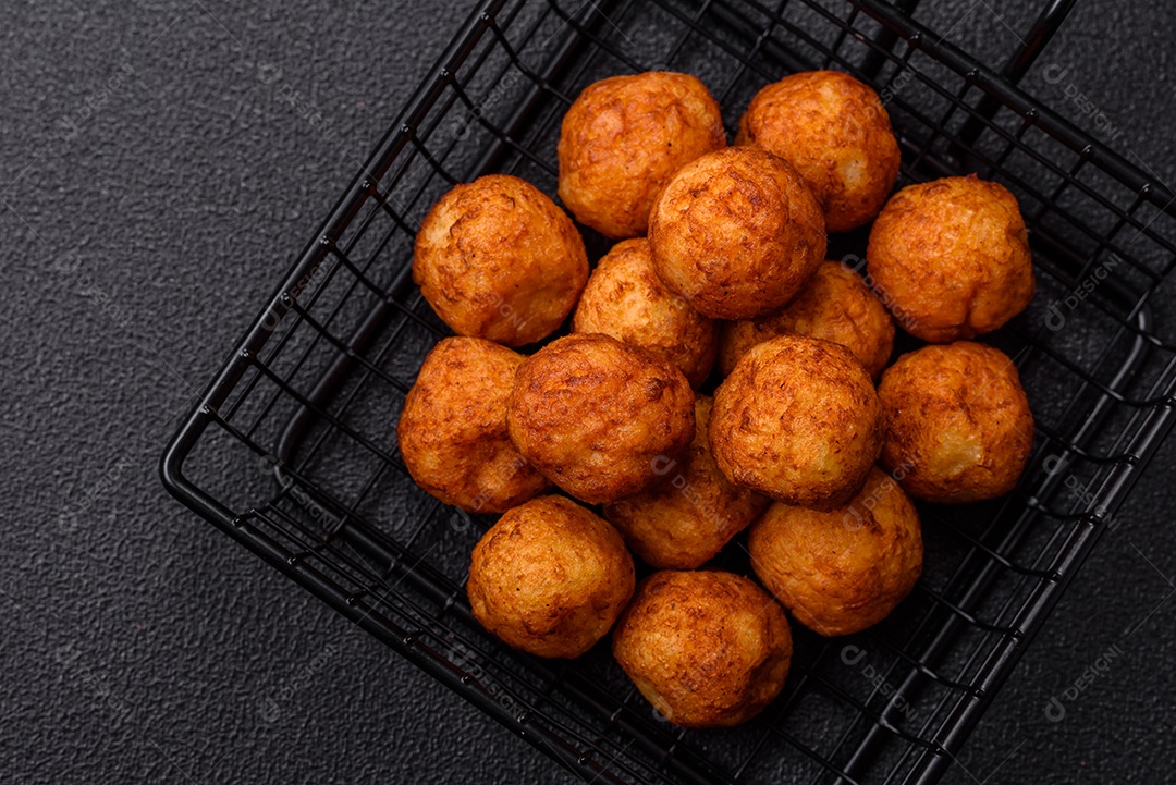 Deliciosas bolas crocantes empanadas com queijo mussarela, sal e especiarias em fundo escuro de concreto