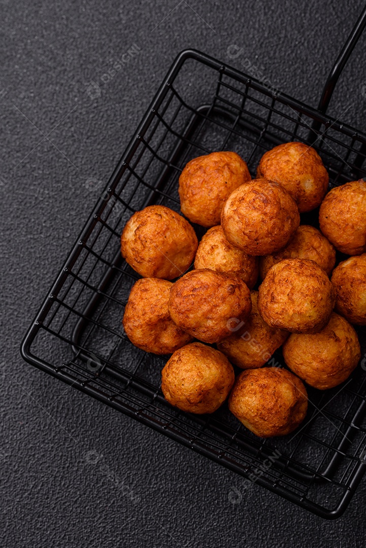 Deliciosas bolas crocantes empanadas com queijo mussarela, sal e especiarias em fundo escuro de concreto