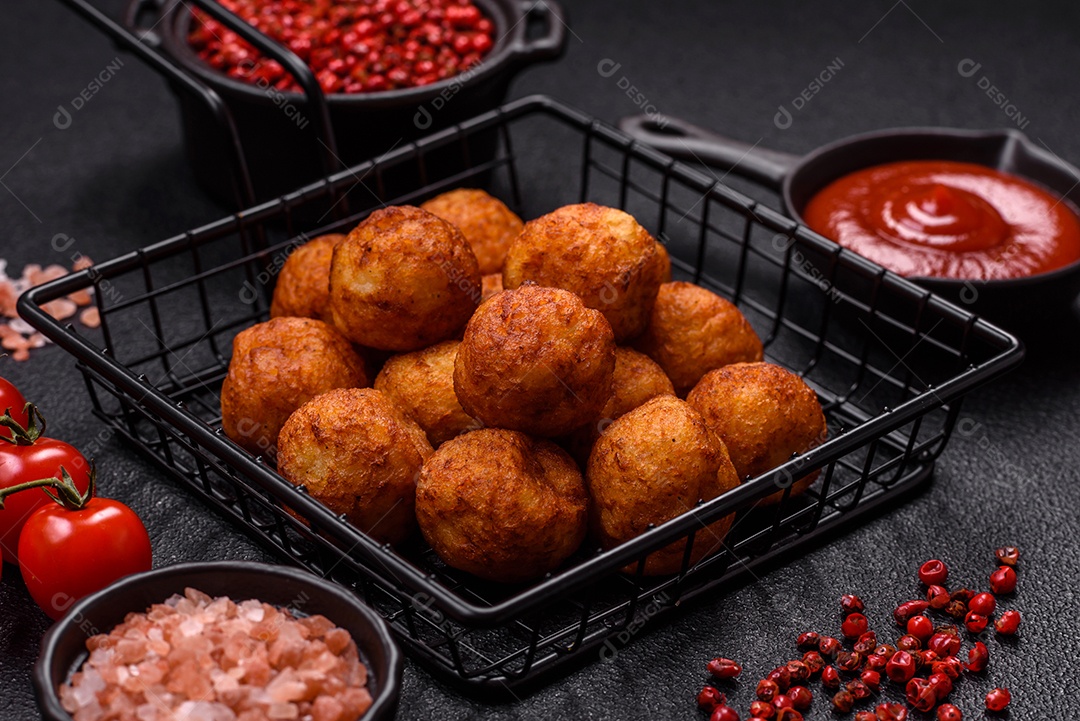 Deliciosas bolas crocantes empanadas com queijo mussarela, sal e especiarias em fundo escuro de concreto