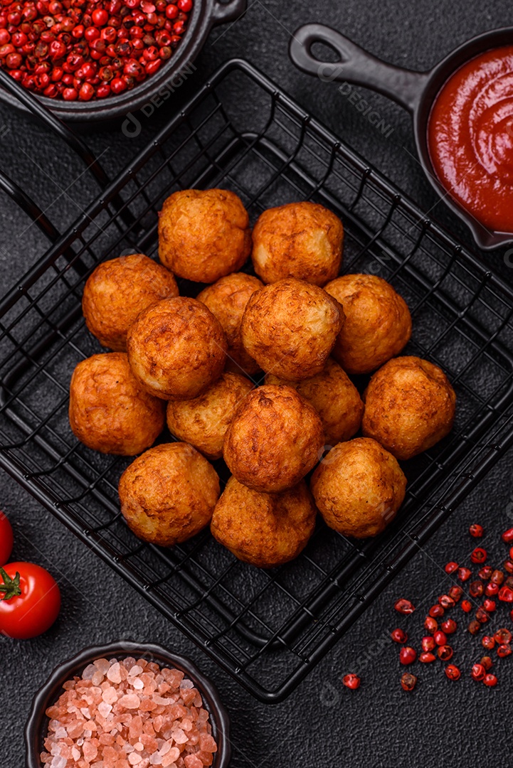 Deliciosas bolas crocantes empanadas com queijo mussarela, sal e especiarias em fundo escuro de concreto