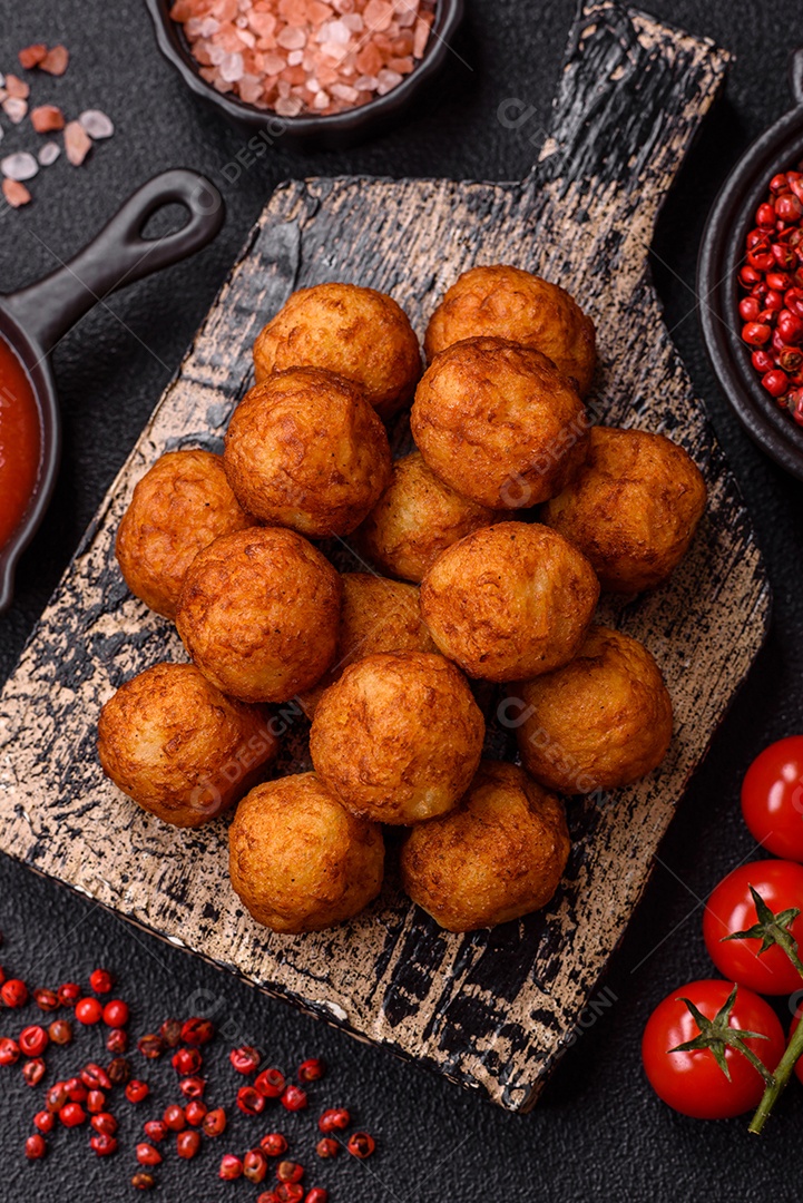 Deliciosas bolas crocantes empanadas com queijo mussarela, sal e especiarias em fundo escuro de concreto