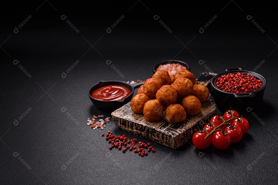 Deliciosas bolas crocantes empanadas com queijo mussarela, sal e especiarias em fundo escuro de concreto