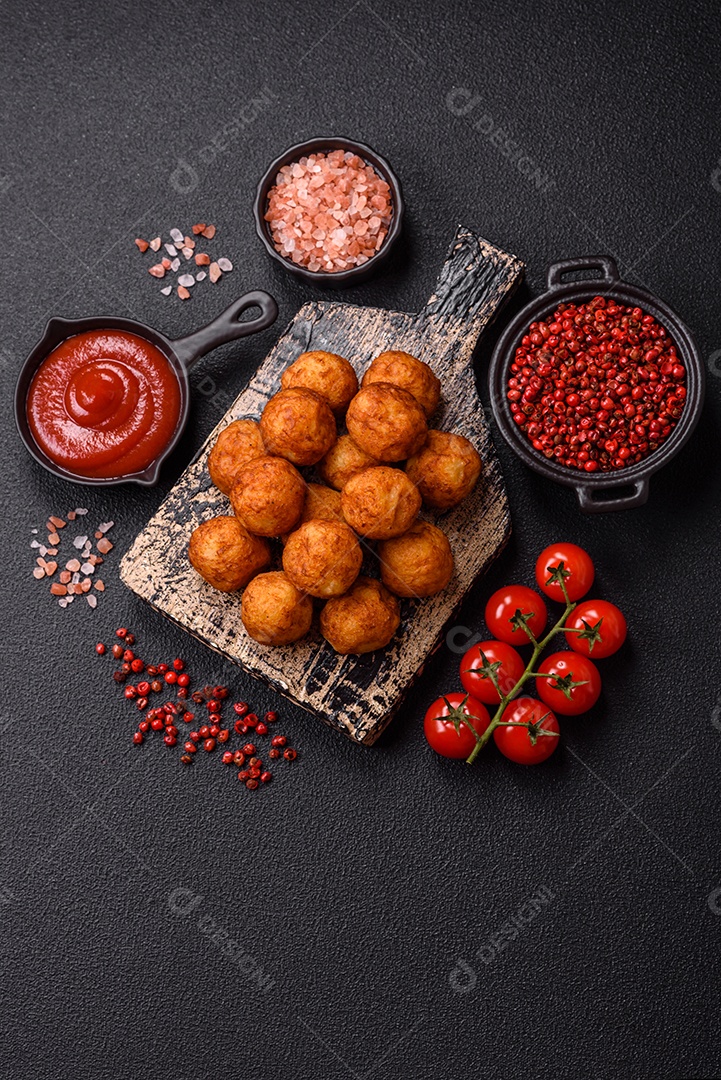 Deliciosas bolas crocantes empanadas com queijo mussarela, sal e especiarias em fundo escuro de concreto