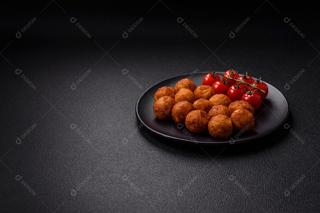 Deliciosas bolas crocantes empanadas com queijo mussarela, sal e especiarias em fundo escuro de concret