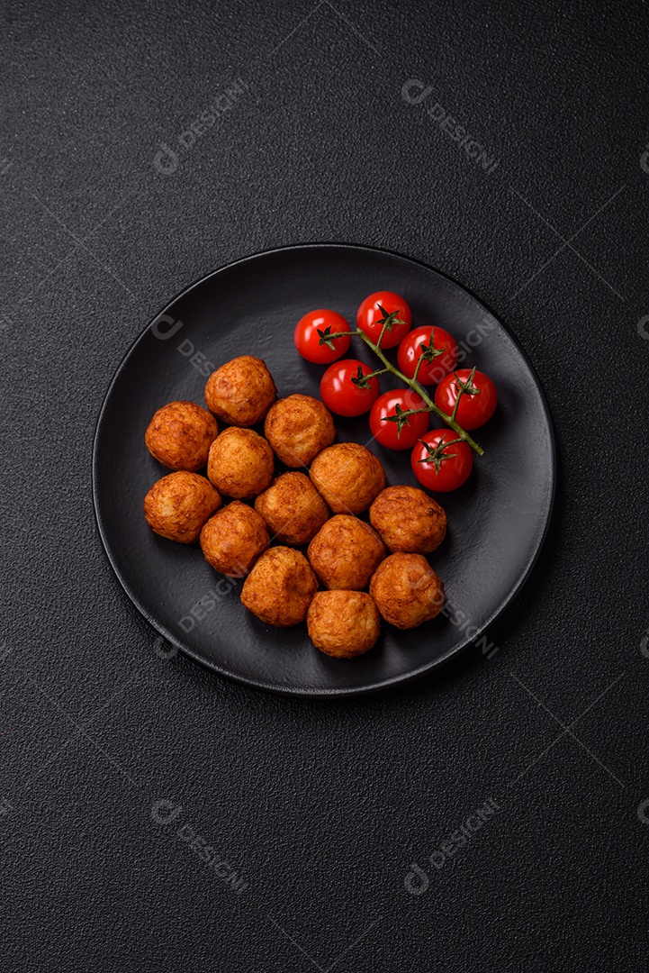 Deliciosas bolas crocantes empanadas com queijo mussarela, sal e especiarias em fundo escuro de concreto