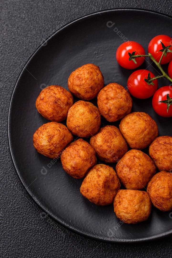Deliciosas bolas crocantes empanadas com queijo mussarela, sal e especiarias em fundo escuro de concreto