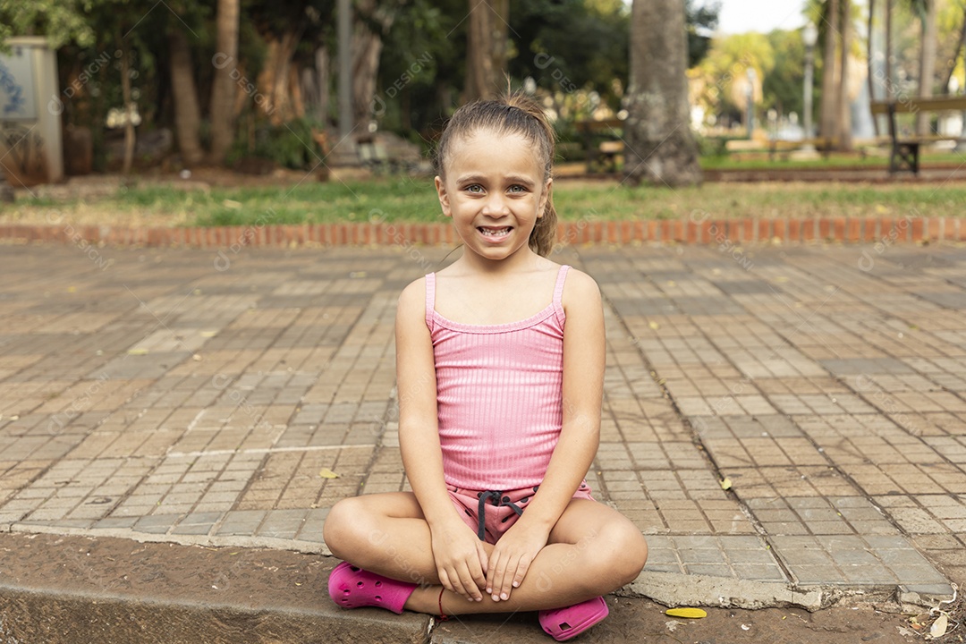 Criança linda sentada na calçada sorrindo