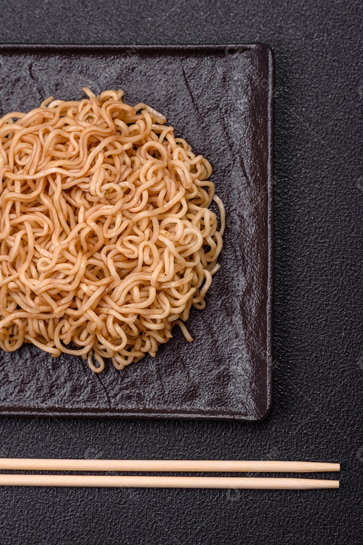 Macarrão de arroz de prato asiático com sal e especiarias em fundo escuro de concreto