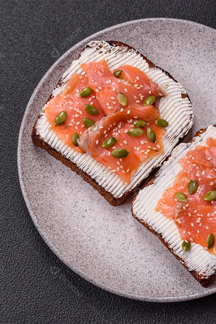 Torradas grelhadas com pasta de abacate, ovos, cream cheese, sal, especiarias e ervas sobre uma mesa de concreto texturizado