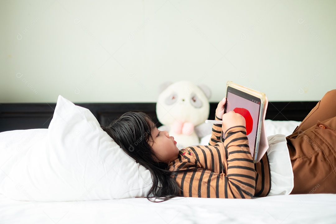 Uma garota deitada asiática brincando com o tablet