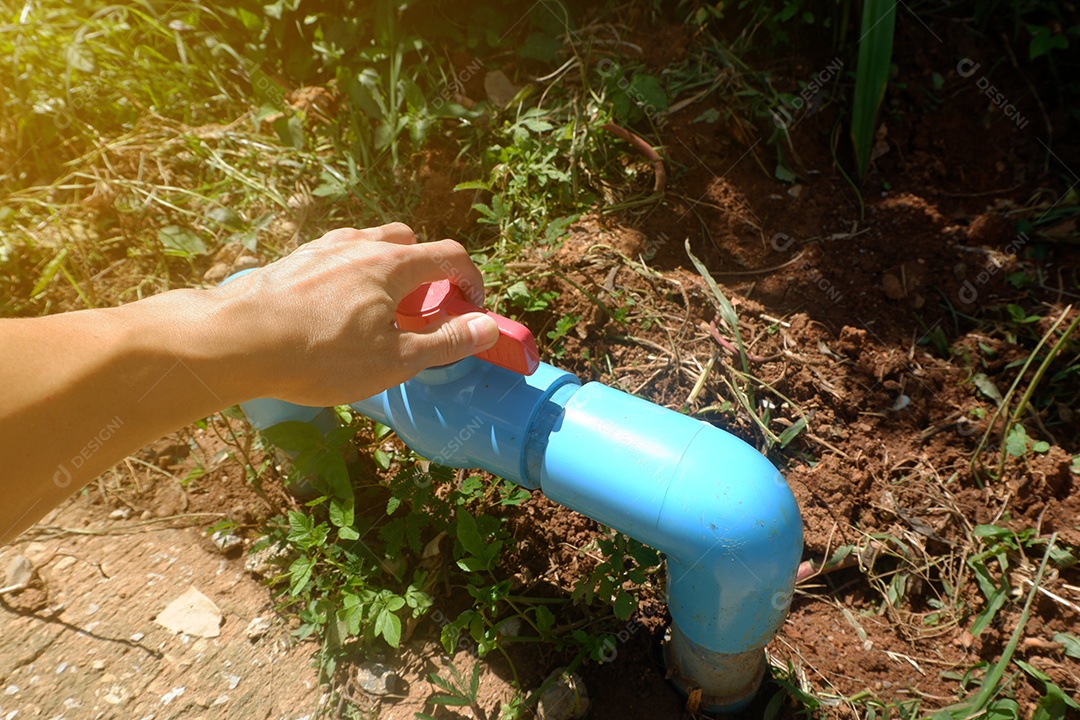 As mãos do homem ajustando a volta de uma grande válvula de água plástica