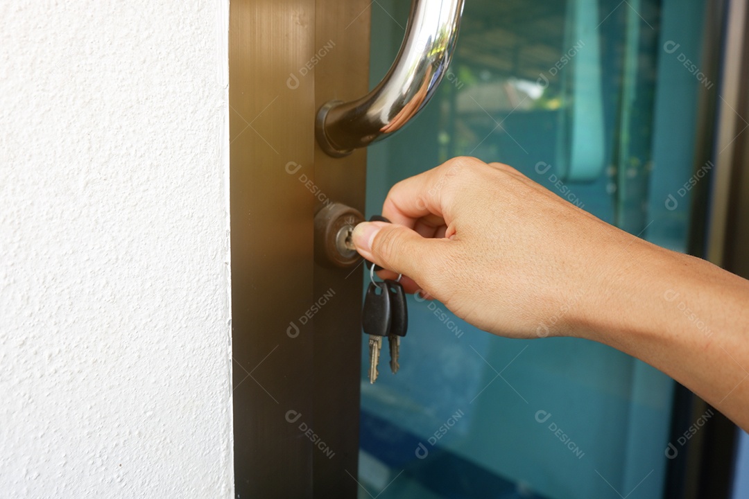 A mão de um homem segura uma chave e a gira para destrancar e abrir a porta