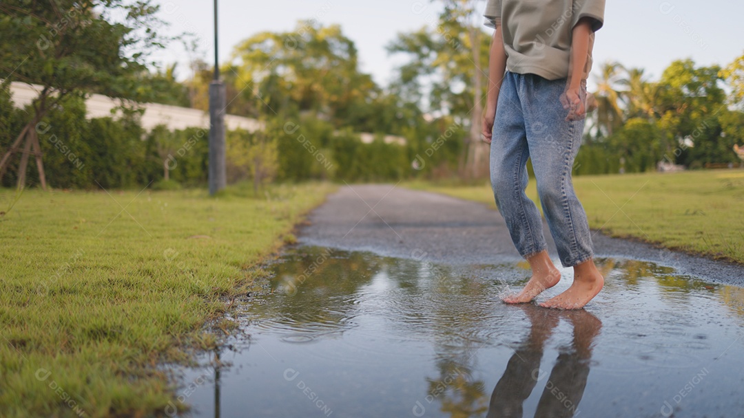 Uma criança se divertindo em uma poça de água no quintal