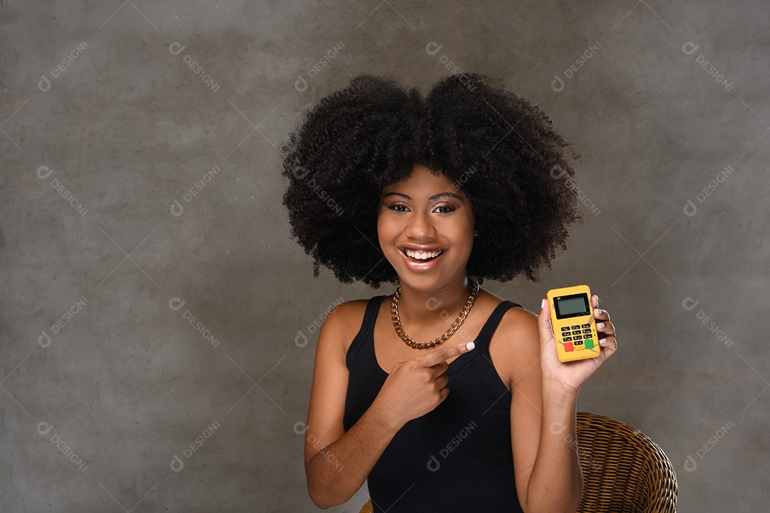 Mulher jovem sorrindo segurando maquina de cartão de crédito