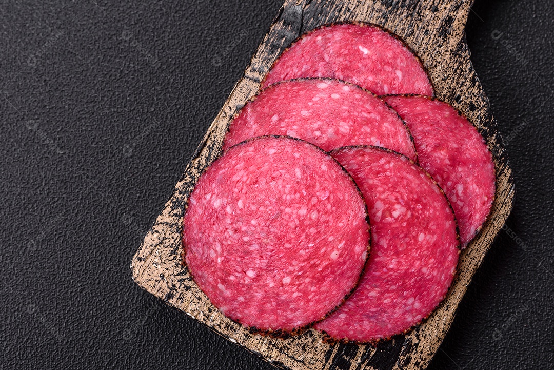 Salame defumado sobre uma tábua de madeira sobre mesa