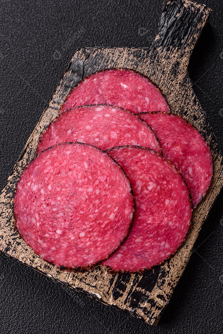 Salame defumado sobre uma tábua de madeira sobre mesa