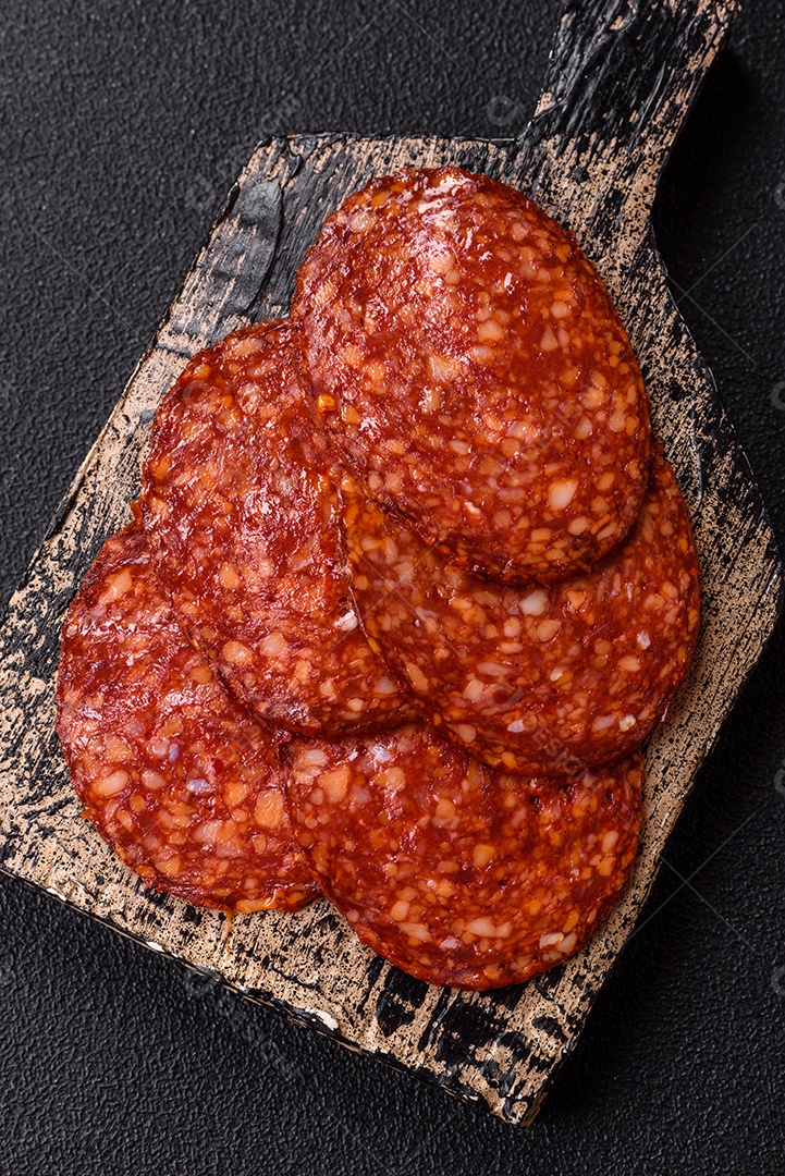 Salame defumado sobre uma tábua de madeira sobre mesa