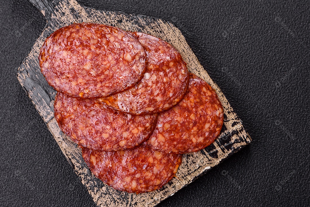 Salame defumado sobre uma tábua de madeira sobre mesa