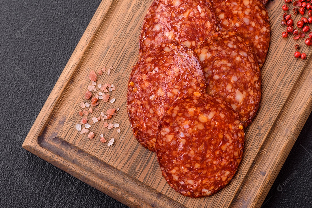 Salame defumado sobre uma tábua de madeira sobre mesa