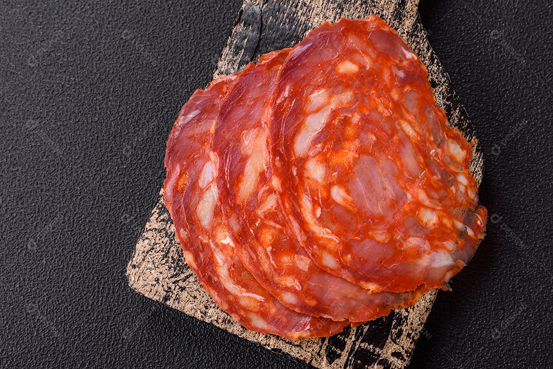 Salame defumado sobre uma tábua de madeira sobre mesa