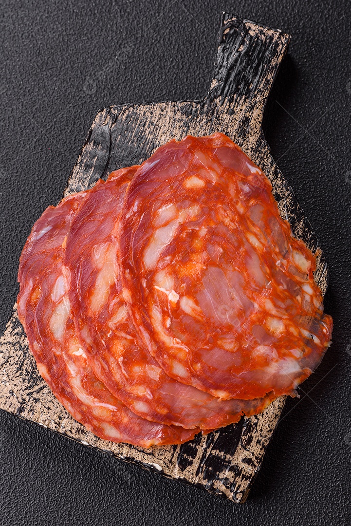 Salame defumado sobre uma tábua de madeira sobre mesa