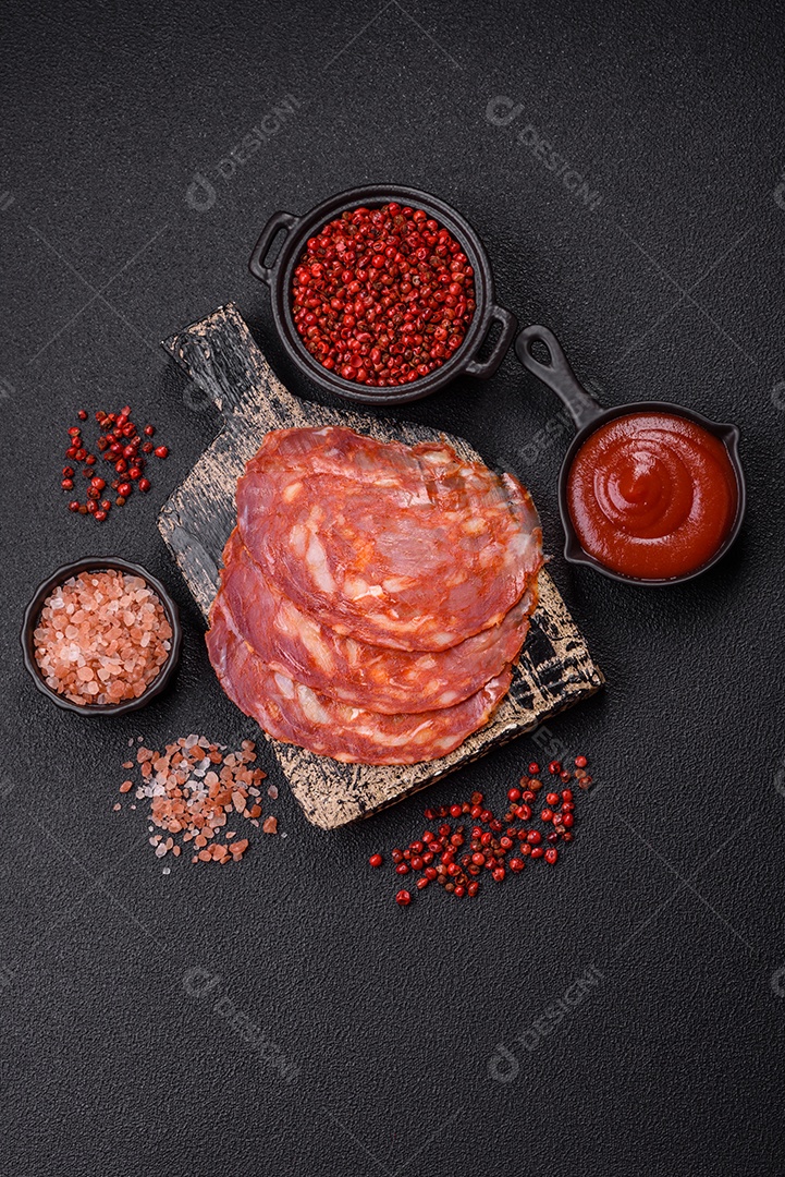 Salame chouriço sobre tábua com molho e temperos ao lado