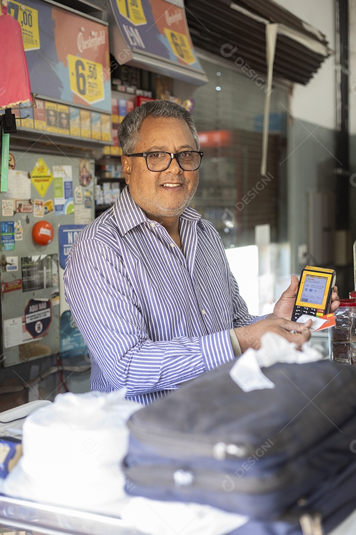 Homem sorrindo com maquina na mão na bancada de loja