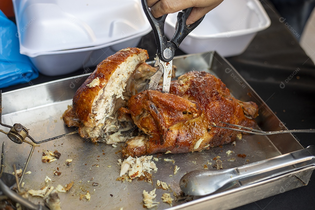 Mãos com tesoura cortando pedaços de frango