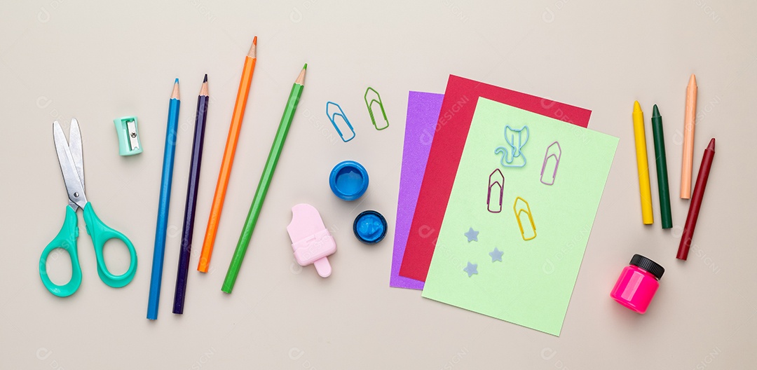 Lápis de cores tesouras clips e apontador e folhas sobre um fundo pastel