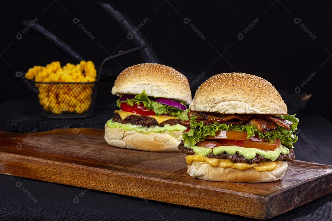 Hamburgueres e cesta de batatas frita sobre tábua de madeira