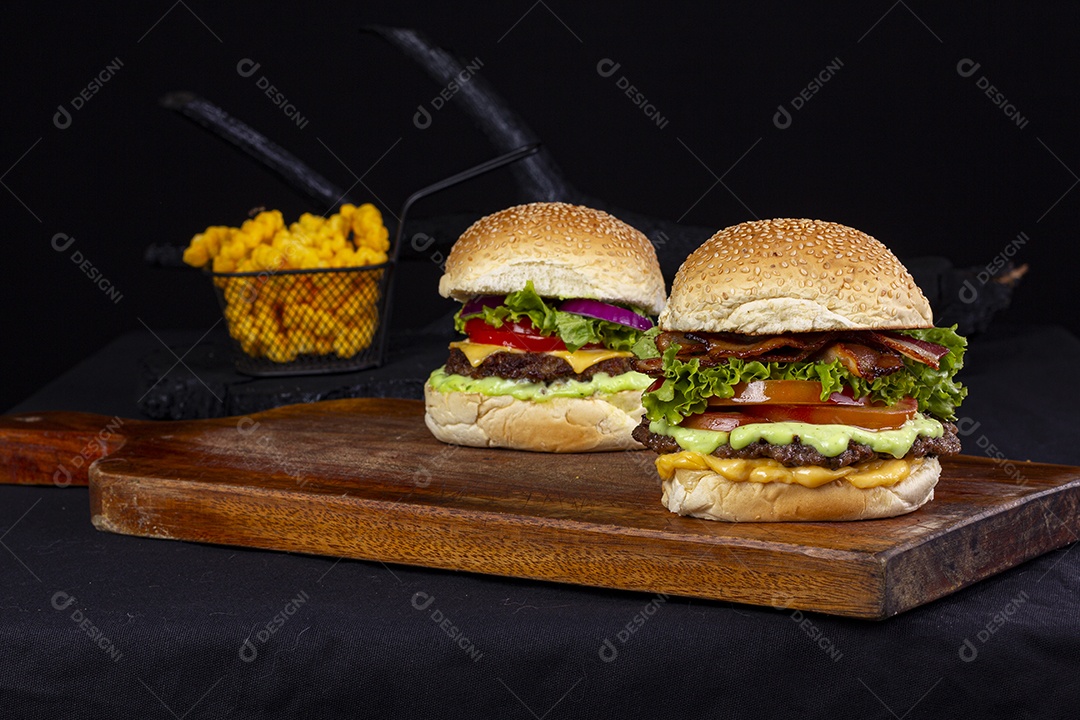 Hamburgueres e cesta de batatas frita sobre tábua de madeira