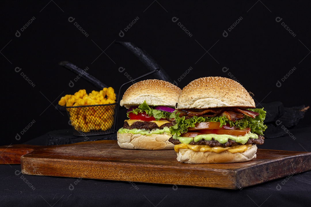 Hamburgueres e cesta de batatas frita sobre tábua de madeira