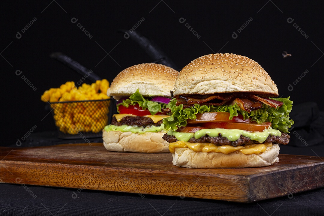 Hamburgueres e cesta de batatas frita sobre tábua de madeira