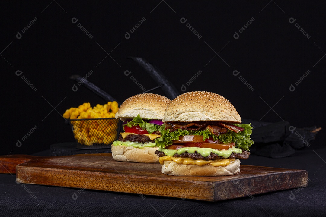 Hamburgueres e cesta de batatas frita sobre tábua de madeira