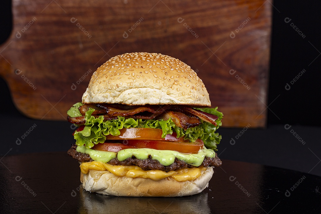 Hamburguer gigante sobre a mesa com tábua de madeira ao fundo