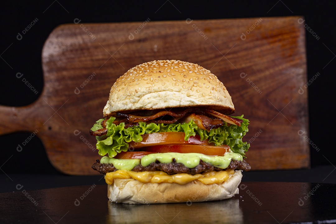 Hamburguer gigante sobre a mesa com tábua de madeira ao fundo