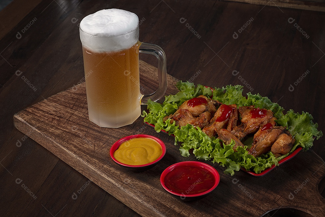 Porção de frango e molhos com caneca de cerveja