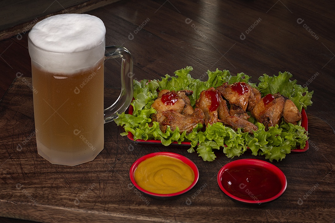 Porção de frango frito com molhos e canecas de cerveja