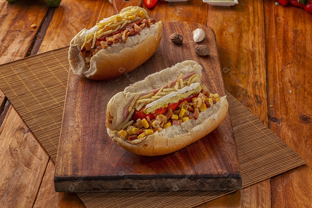 Dois cachorro quentes recheados sobre tábua de madeira