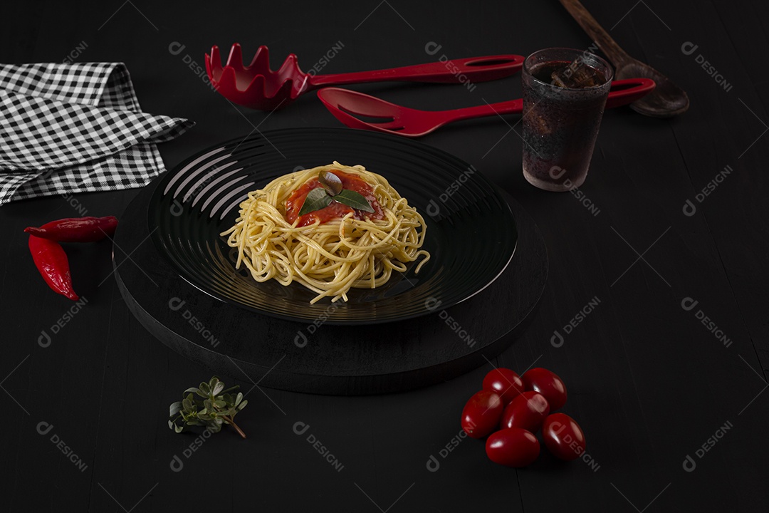 Macarrão com molho de tomate em um prato preto