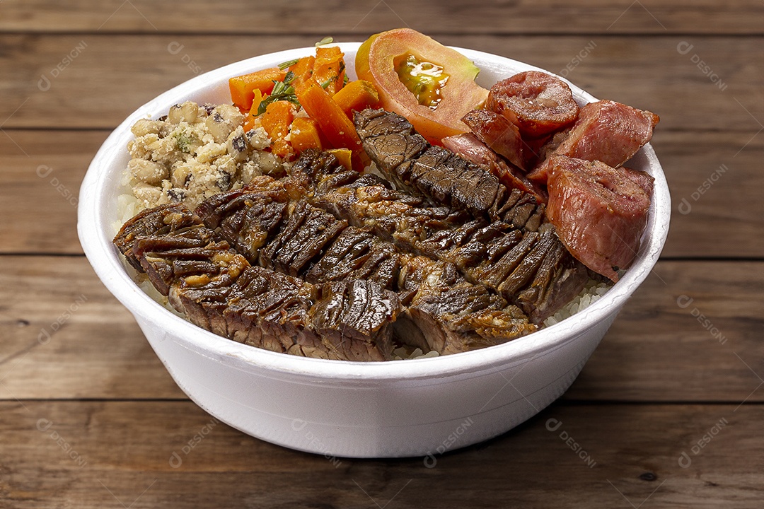 Marmita de churrasco com salada de tomate e arroz sobre mesa de madeira