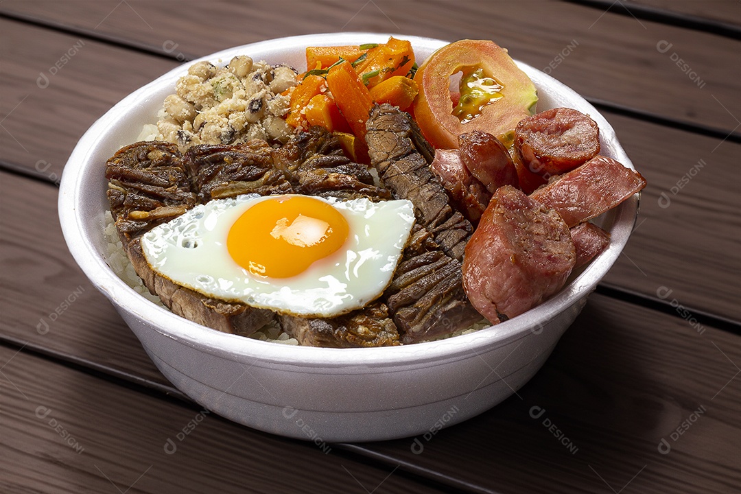 Arroz salada churrasco e ovo frito em marmita sobre a mesa