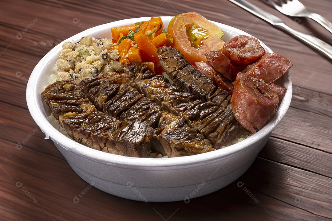 Marmita de churrasco com salada sobre mesa de madeira