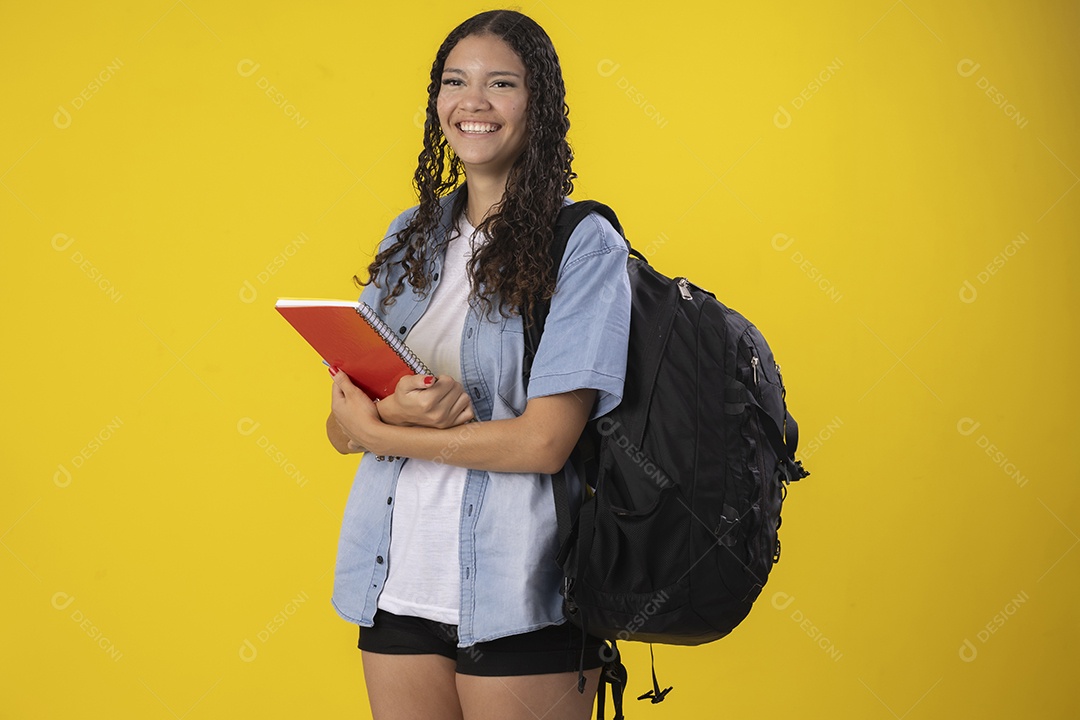 Jovem estudante segurando caderno nas mãos e mochila nas costas