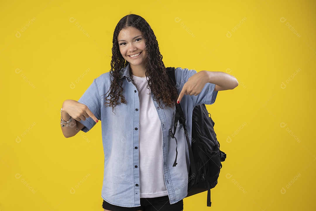 Jovem apontando para baixo com mochila nas costa
