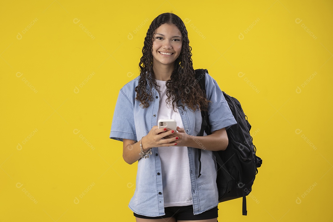 Jovem estudante com camisa jeans e com celular e mochila