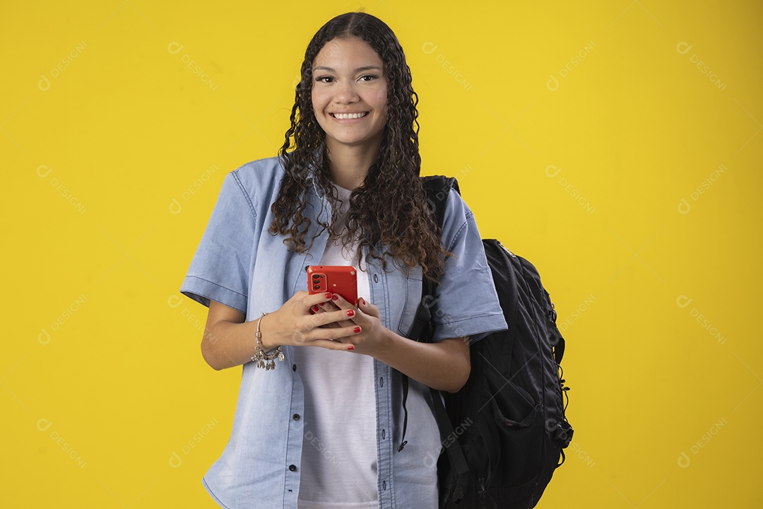 Jovem estudante com camisa jeans e com celular e mochila