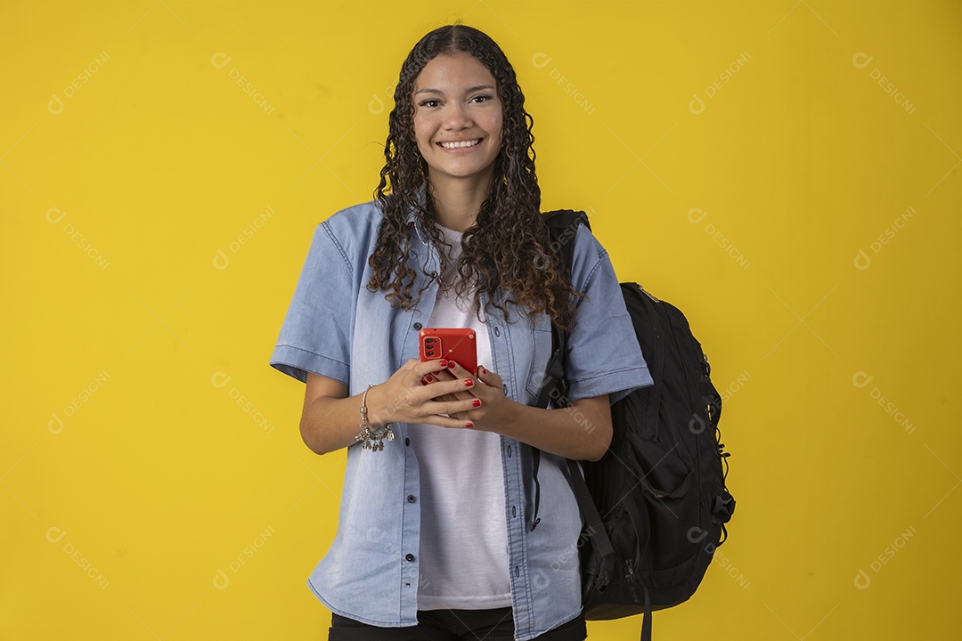 Jovem estudante com camisa jeans e com celular e mochila